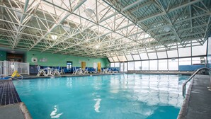 Una piscina interior con techo alto y paredes de vidrio transparente.