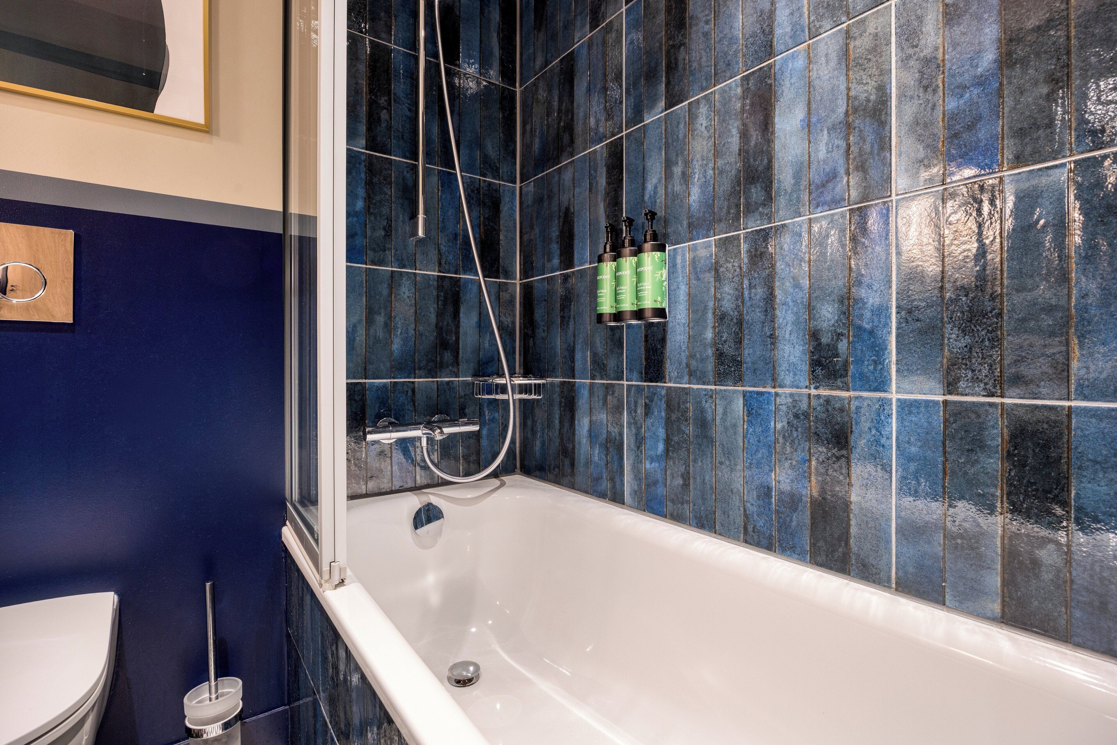 A bathroom with a bathtub, a toilet, and a shower area.