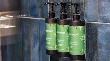 Tres botellas de productos Antipodes sobre una pared de baldosas.