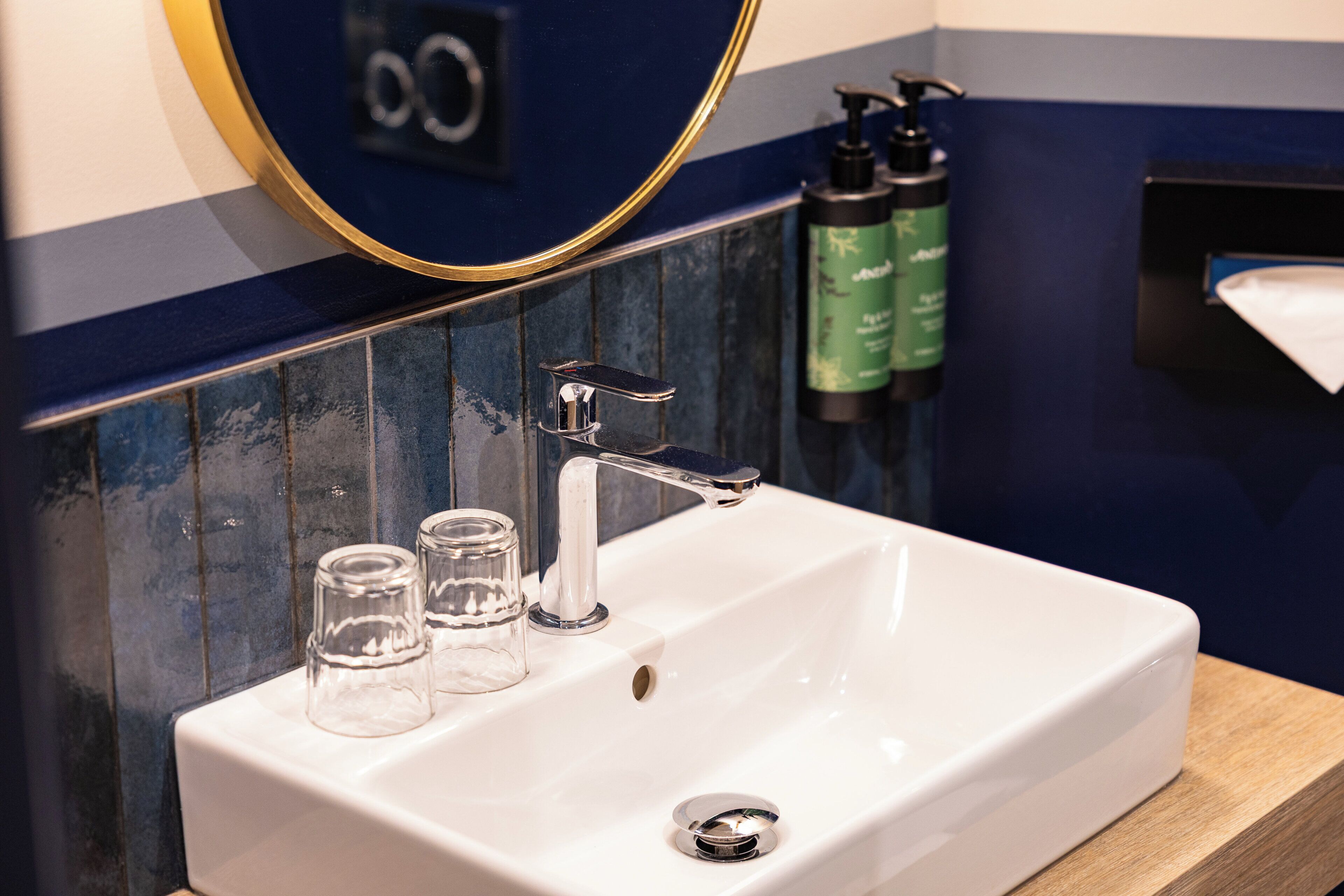 Ein Badezimmer mit Waschbecken, Spiegel und Seifenspender.