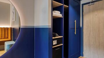A modern room with a curved wall, a wooden bench, a wardrobe with a blue door, and a small black appliance.