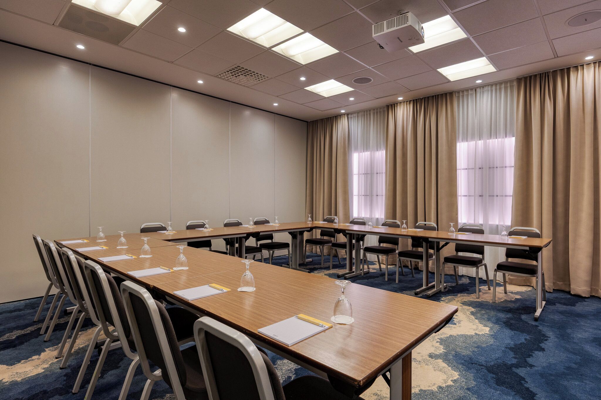 Un salón de conferencias con una larga mesa, sillas y un proyector.