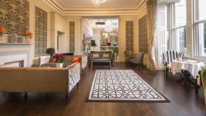 Amplia sala de estar con chimenea, candelabro y comedor con una mesa dispuesta para dos.
