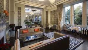 Un hall amplio con un sofá, sillones, una mesa de centro y un candelabro.