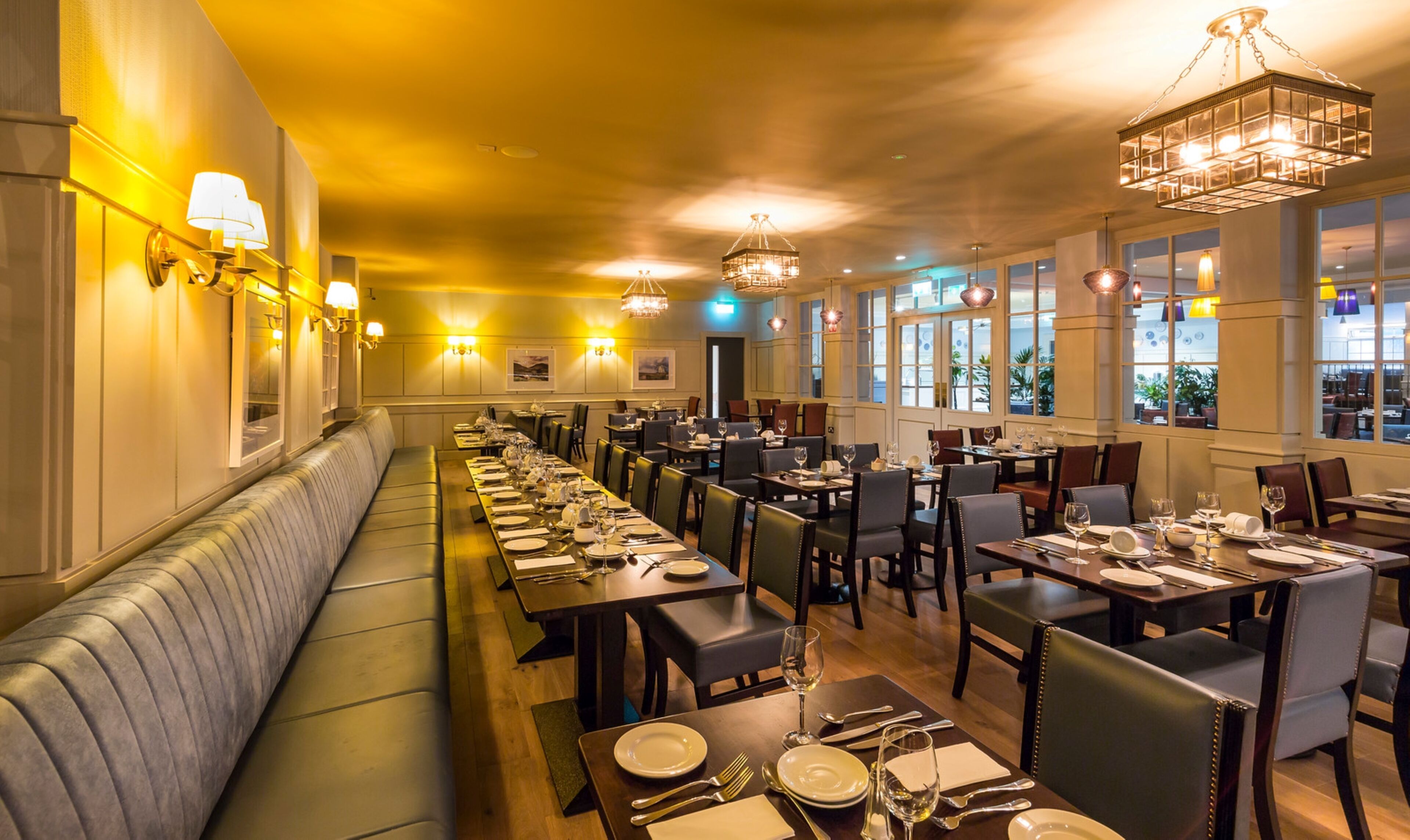 A restaurant with a long counter, multiple tables, and a bench along the wall.