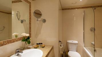 A bathroom with a sink, mirror, toilet, and shower.