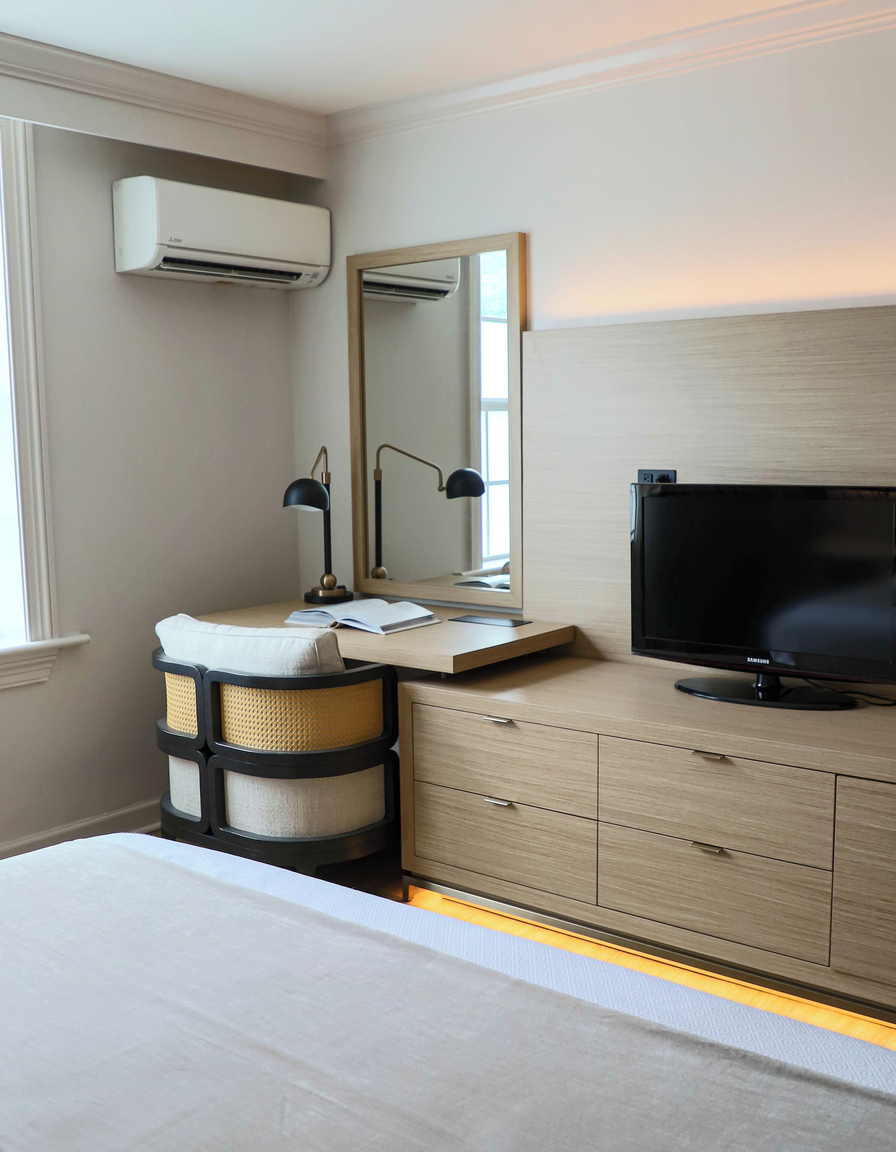 Une chambre d’hôtel équipée d’un lit, d’un bureau avec une lampe, d’une télévision et d’un appareil de climatisation.