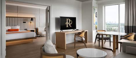 A modern hotel room with a bed, a desk, a TV, a dining table, and a sofa.