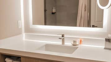 A bathroom with a large mirror, a sink, a towel rack, and a shower curtain.
