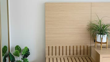 Un dormitorio minimalista con una cama de madera, una planta en la mesita de noche y un espejo.