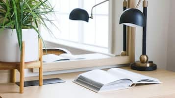 A desk with a plant, a lamp, and an open book.