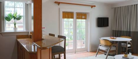 A dining area with a wooden table and chairs, a small round table with a white tablecloth, and a ceiling fan.