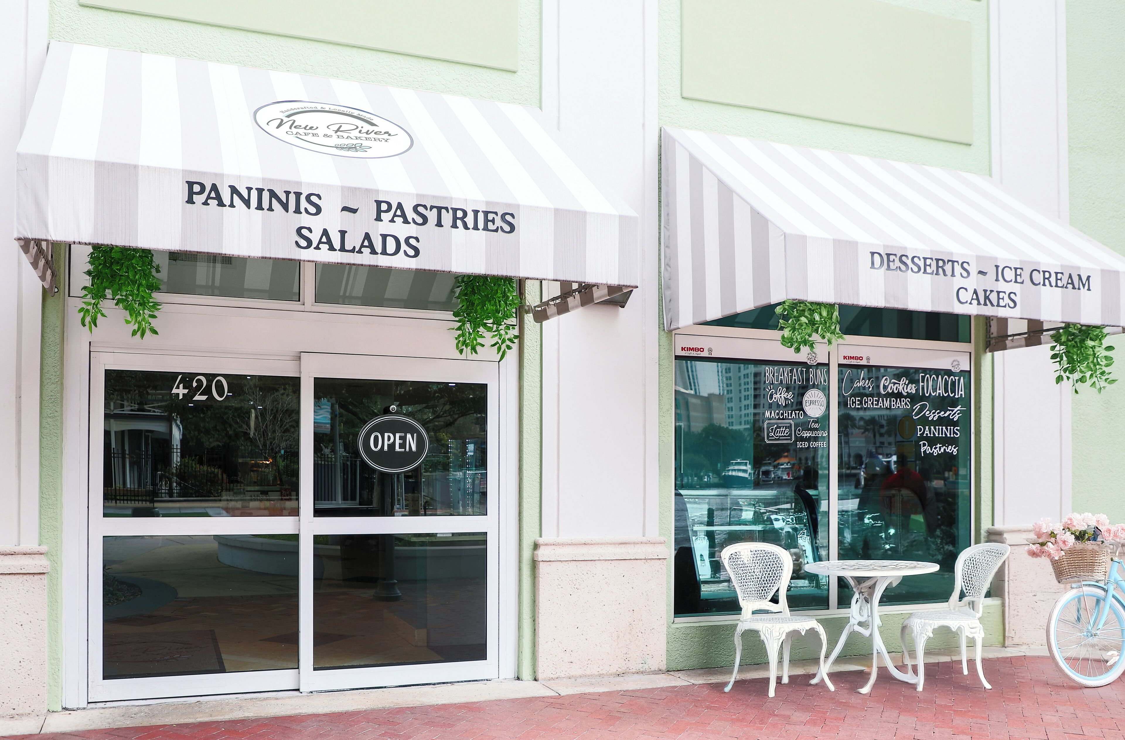 A storefront with awnings labeled "PANINIS - PASTRIES SALADS" and "DESSERTS - ICE CREAM CAKES".