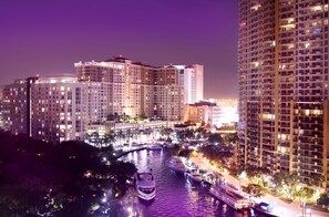 A nighttime view of a cityscape with high-rise buildings, a river with boats, and well-lit streets. - Riverside Hotel (Fort Lauderdale)