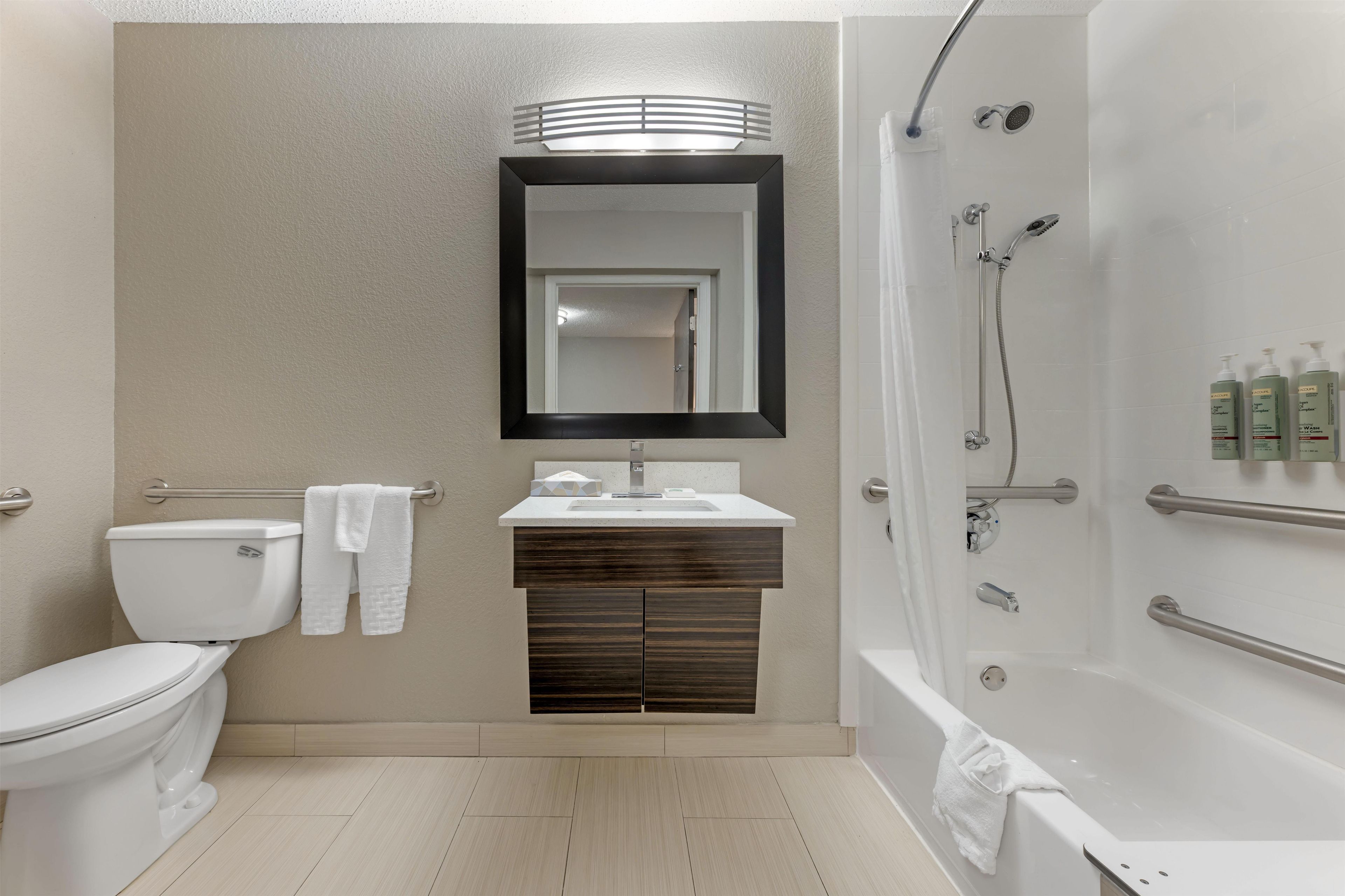 Un baño moderno con inodoro, lavamanos, espejo y ducha.