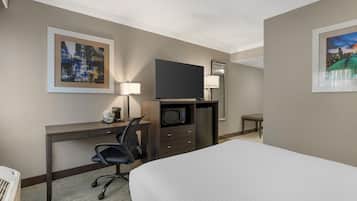 Habitació d'hotel amb llit, escriptori amb cadira, televisió de pantalla plana, microones, cafetera i taula petita.