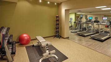 Un gimnasio con cintas de correr, elípticas y pesas libres.