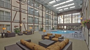 Un espacio interior amplio con piscina, zonas de estar y ventanas grandes.