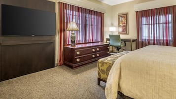 Een hotelkamer met een groot bed, een kast, een bureau, een stoel en een televisie.