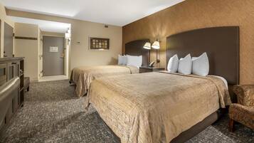 Habitación de hotel con dos camas, un escritorio, una silla y la puerta del baño.