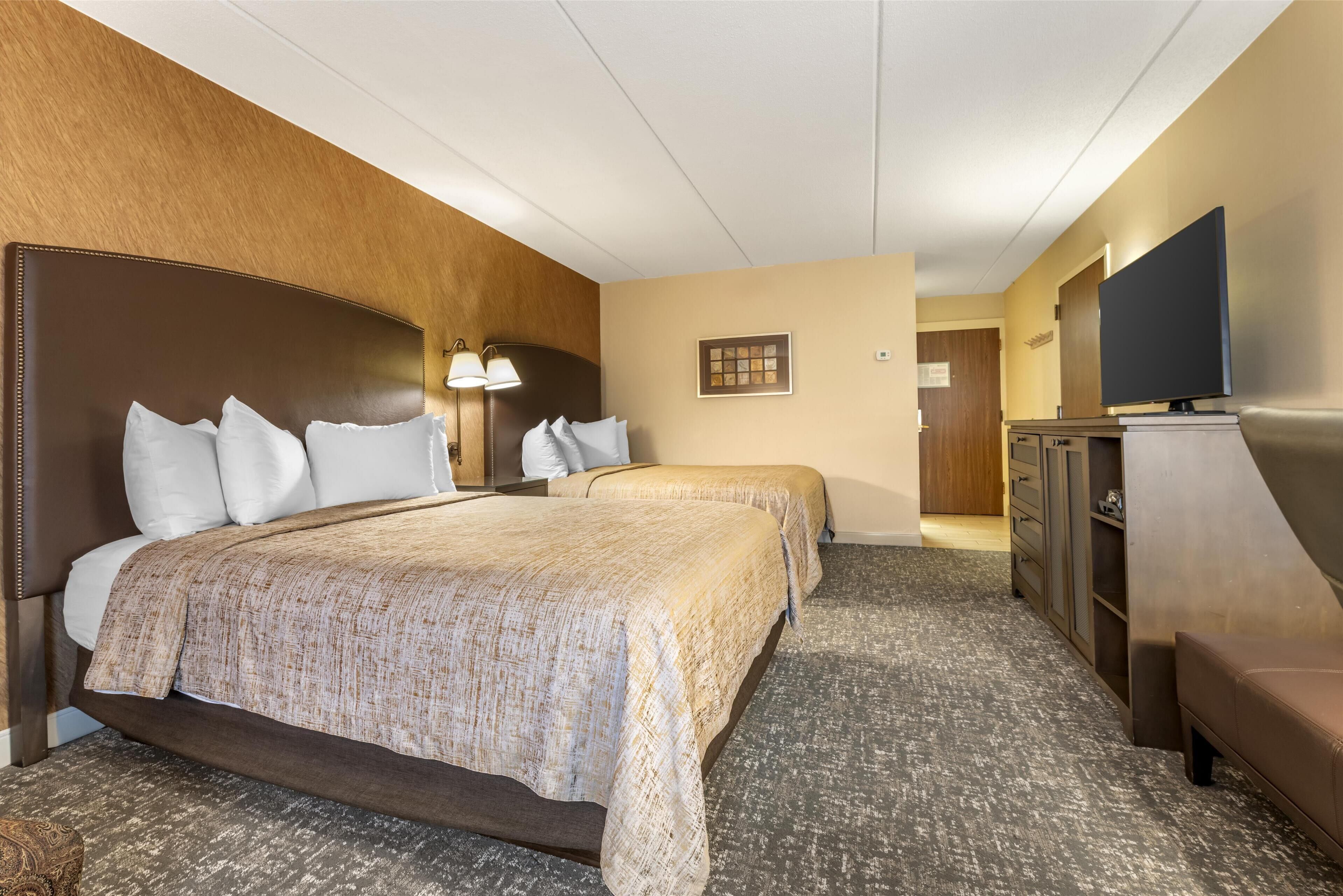 A hotel room with a large bed, two bedside tables, a TV, and a wardrobe.