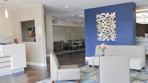 A hotel lobby with a reception desk, seating area, and a decorative wall.