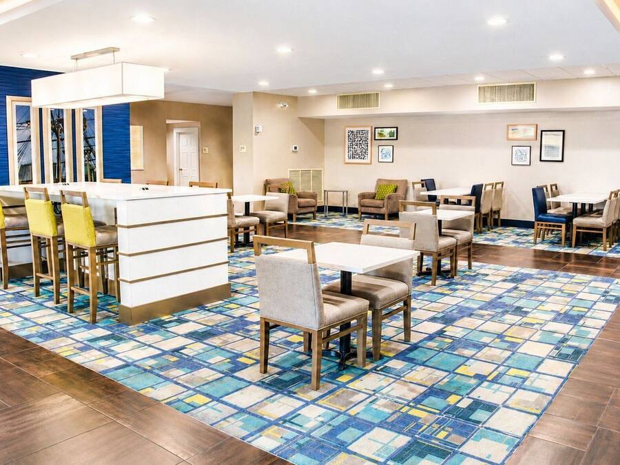 A hotel dining area with multiple tables and chairs, a patterned floor, and artwork on the walls.