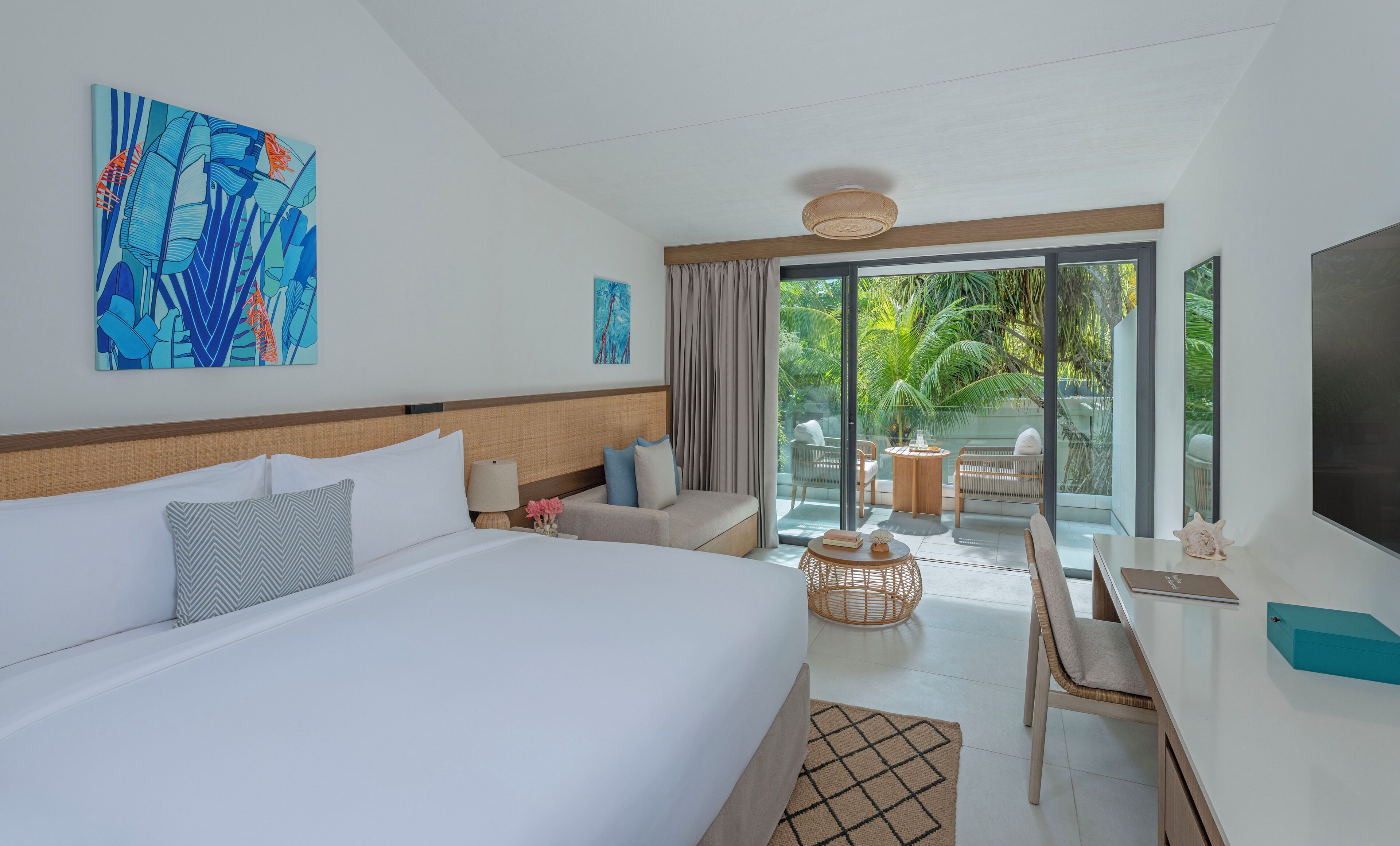 Une chambre d’hôtel avec un grand lit, un bureau, une chaise, une télévision et une vue sur un jardin.
