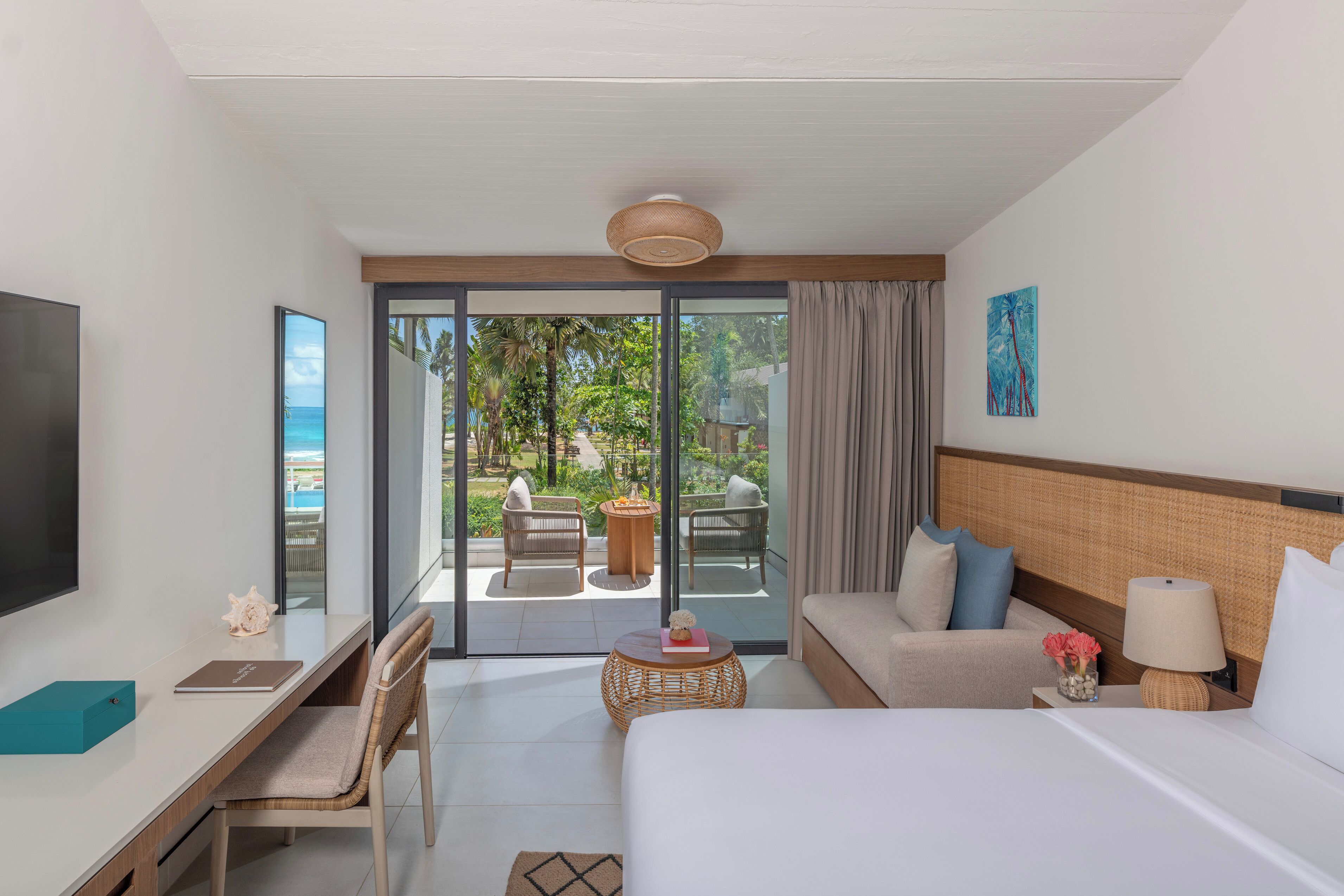 A hotel room with a bed, a desk, a chair, a TV, a window, and a view of the outdoor area.
