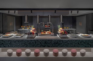 Una cocina moderna con una zona de cocción central, distintas estaciones de comida y un sistema tipo bufé.