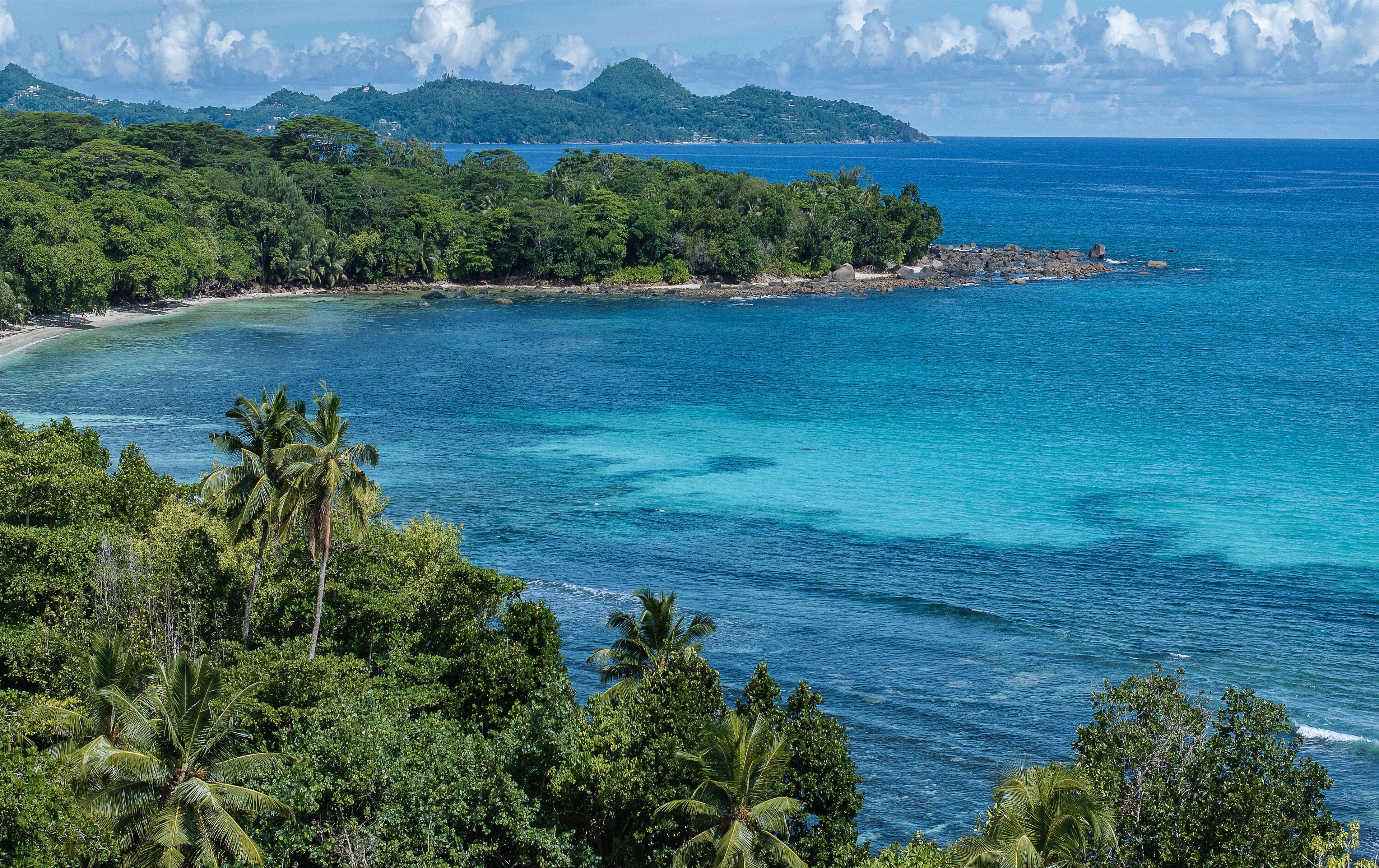 Un paysage côtier caractérisé par une végétation luxuriante et des eaux d’un bleu limpide.