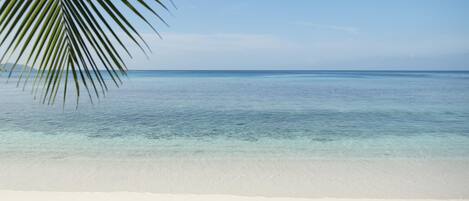 A beach with clear turquoise water and white sand.