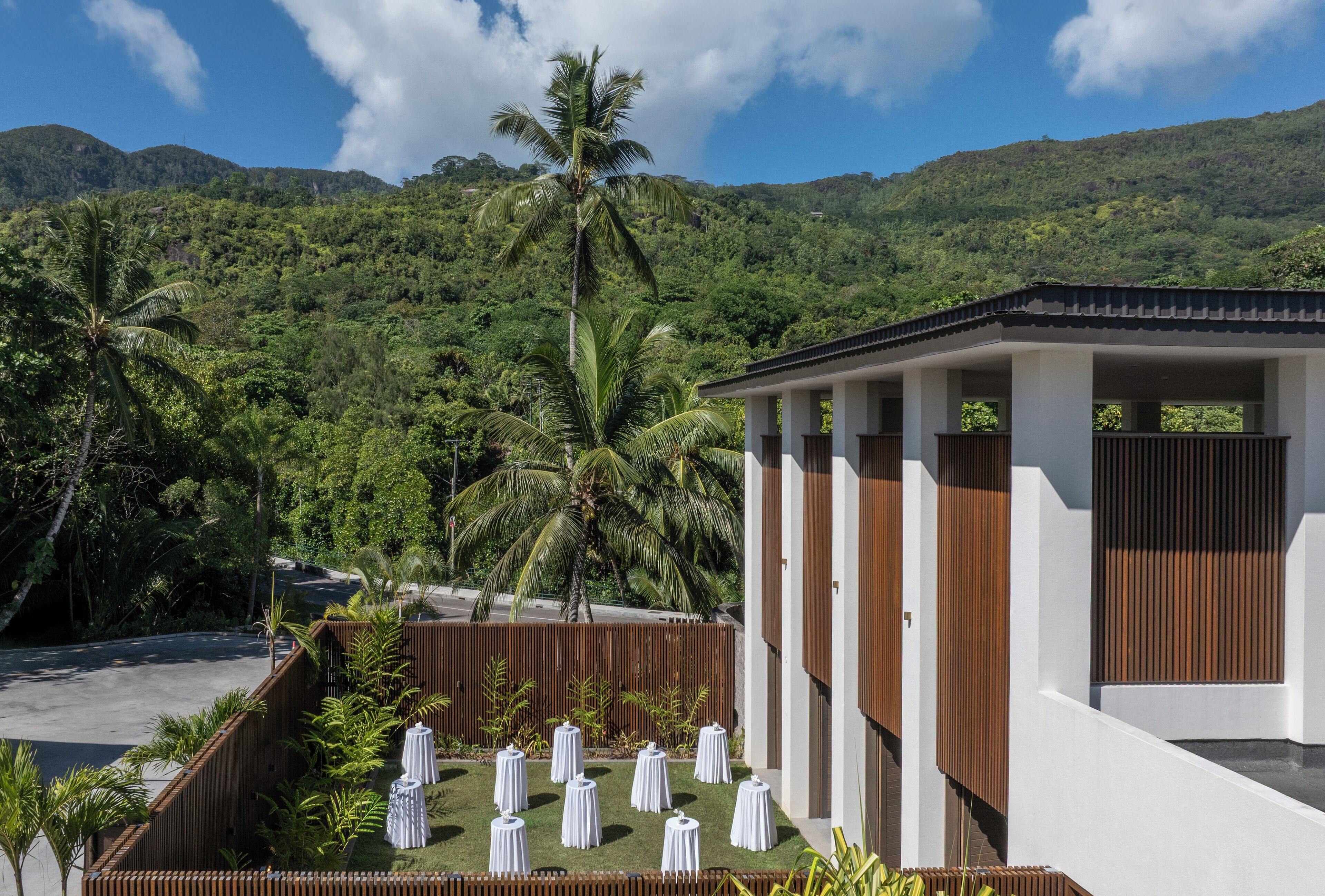 Un resort con piscina, palmeras y vistas a una cadena montañosa.