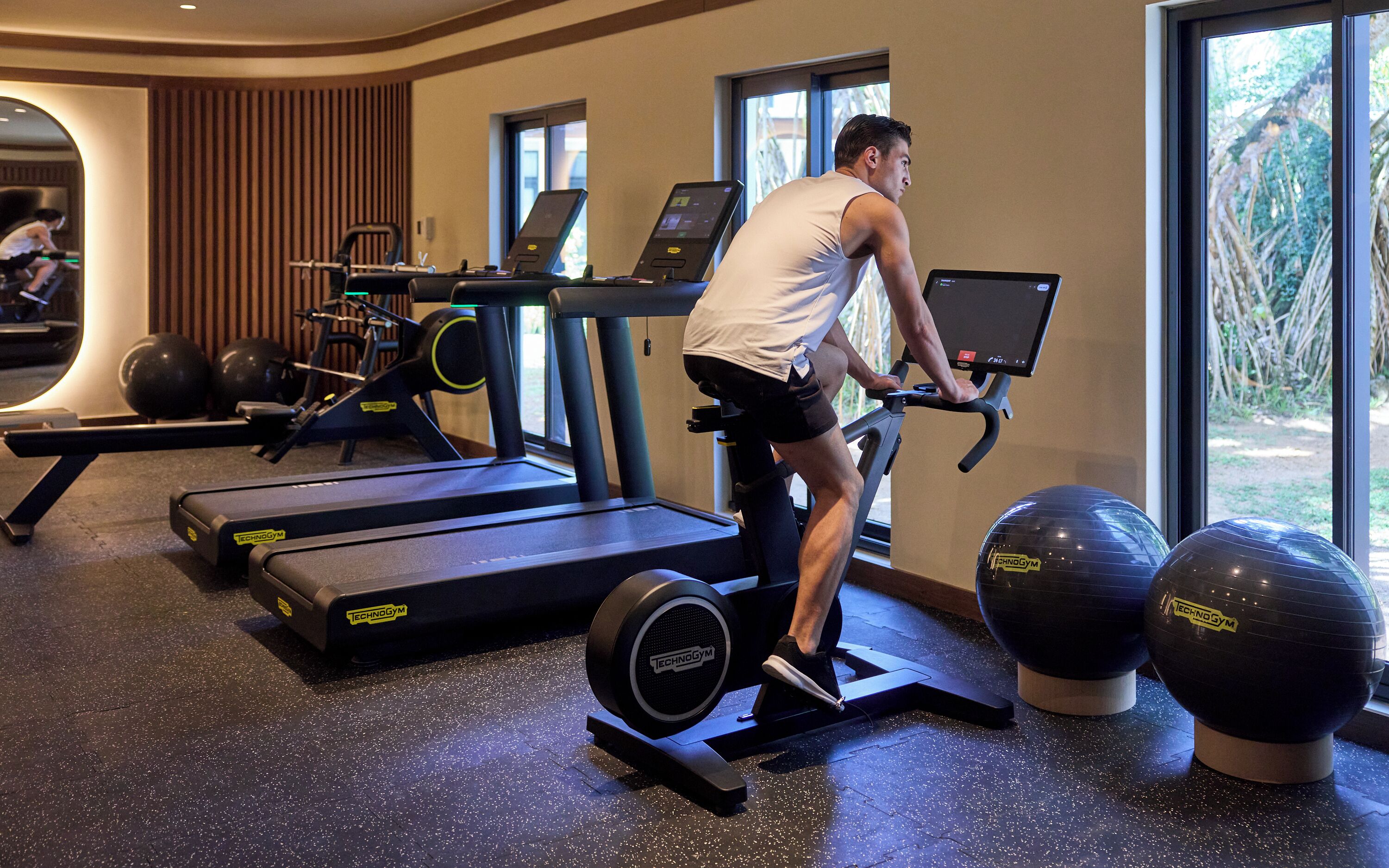 A gym with treadmills, exercise balls, and a mirrored wall.