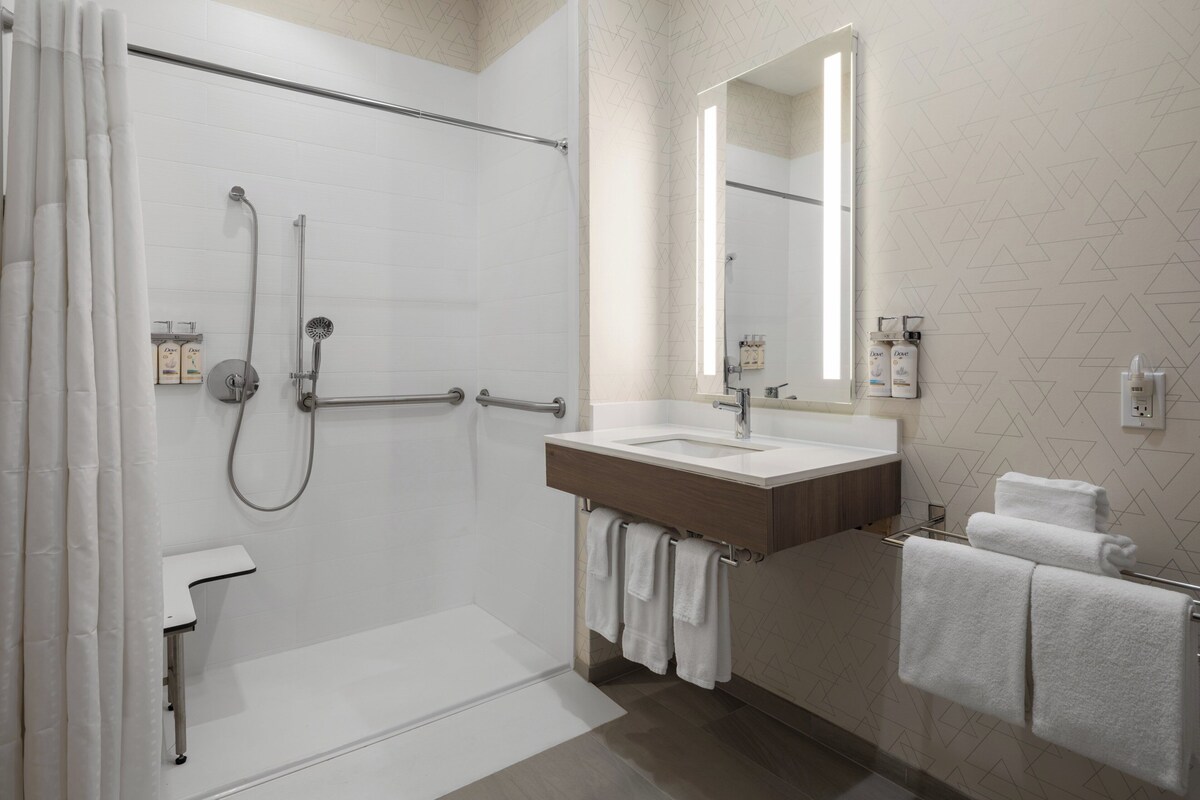 A modern bathroom with a walk-in shower, a vanity with a mirror, and a towel rack.