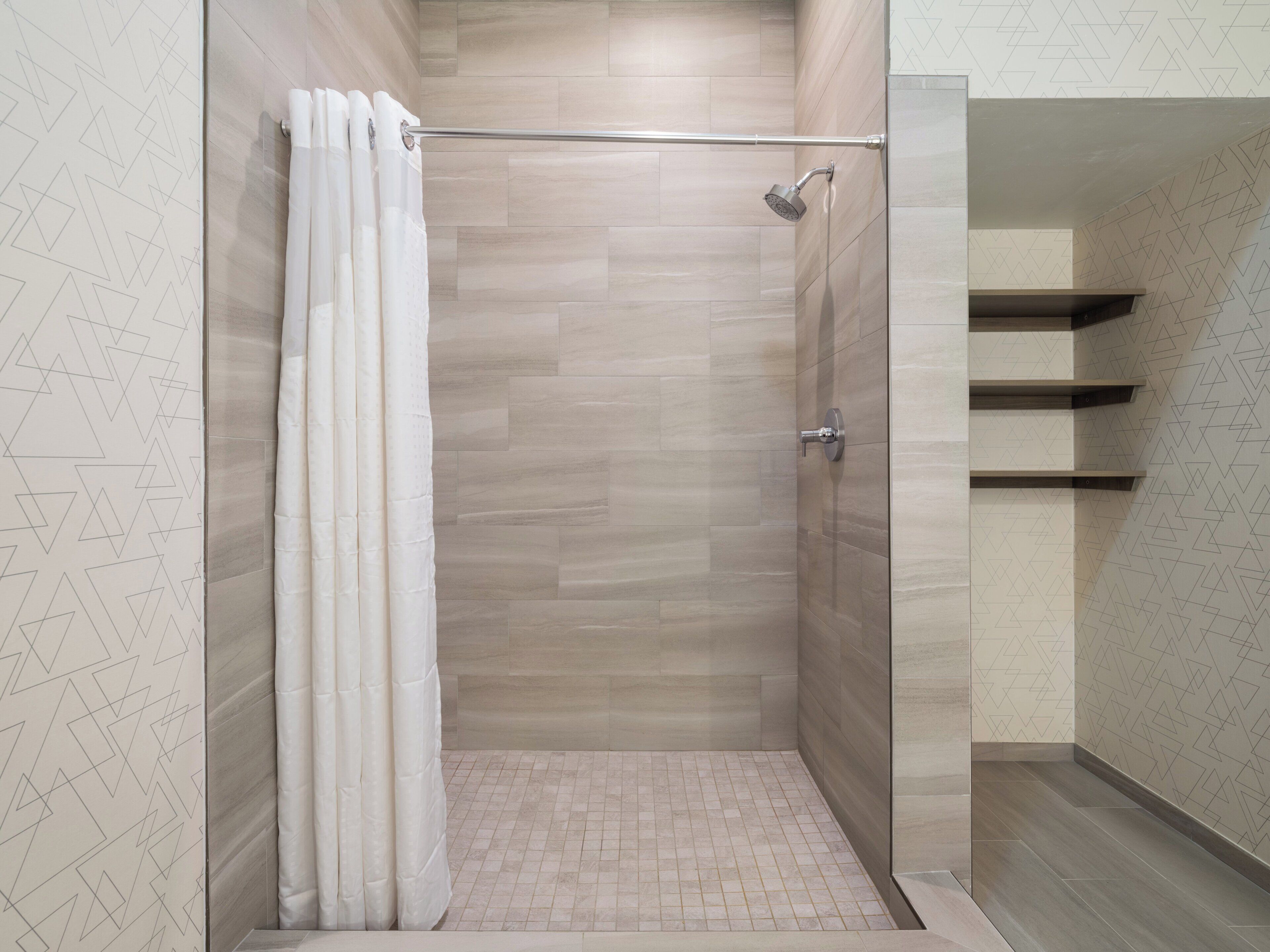 A shower area with a glass door, a showerhead, and a tiled floor.