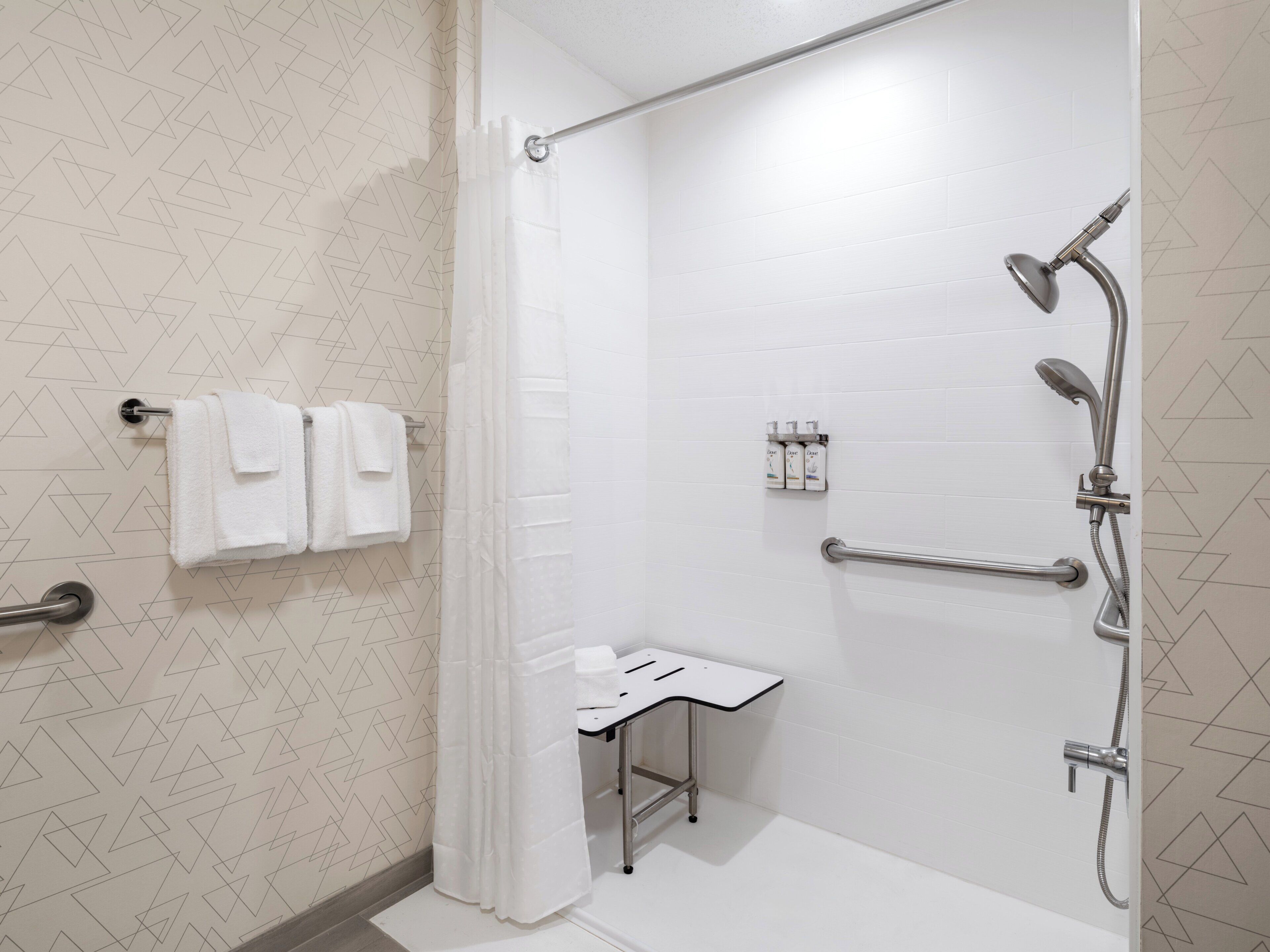 Une salle de bain moderne avec une douche, un petit lavabo et un porte-serviettes.