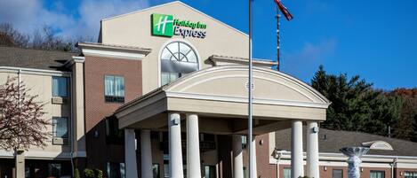 A Holiday Inn Express building with a prominent American flag, a covered entrance with columns, and a brick facade.