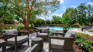 Outdoor wicker furniture, a pool, and lush greenery. - DoubleTree by Hilton Raleigh Midtown, NC (Raleigh)