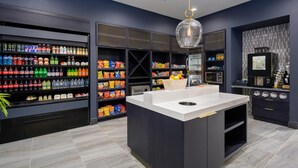 A modern kitchen with a central island, built-in appliances, and a variety of food and drink products on shelves. - DoubleTree by Hilton Raleigh Midtown, NC (Raleigh)