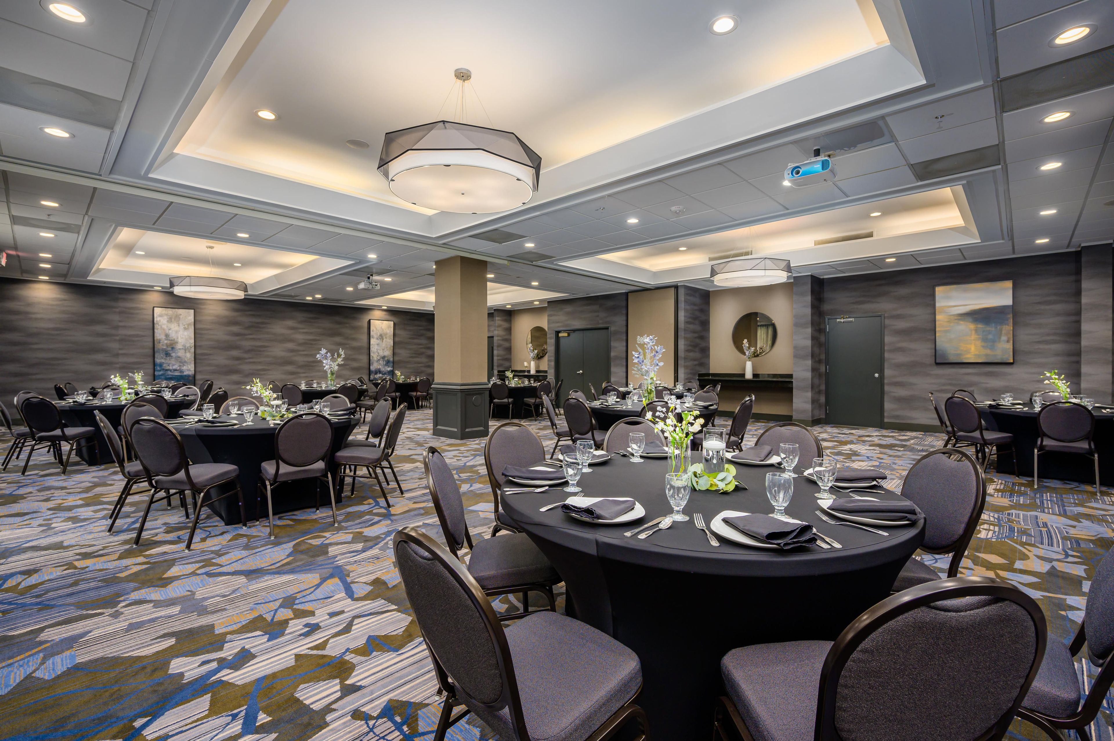 A conference room with round tables, chairs, and a carpeted floor.