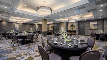 A conference room with round tables, chairs, and a carpeted floor.