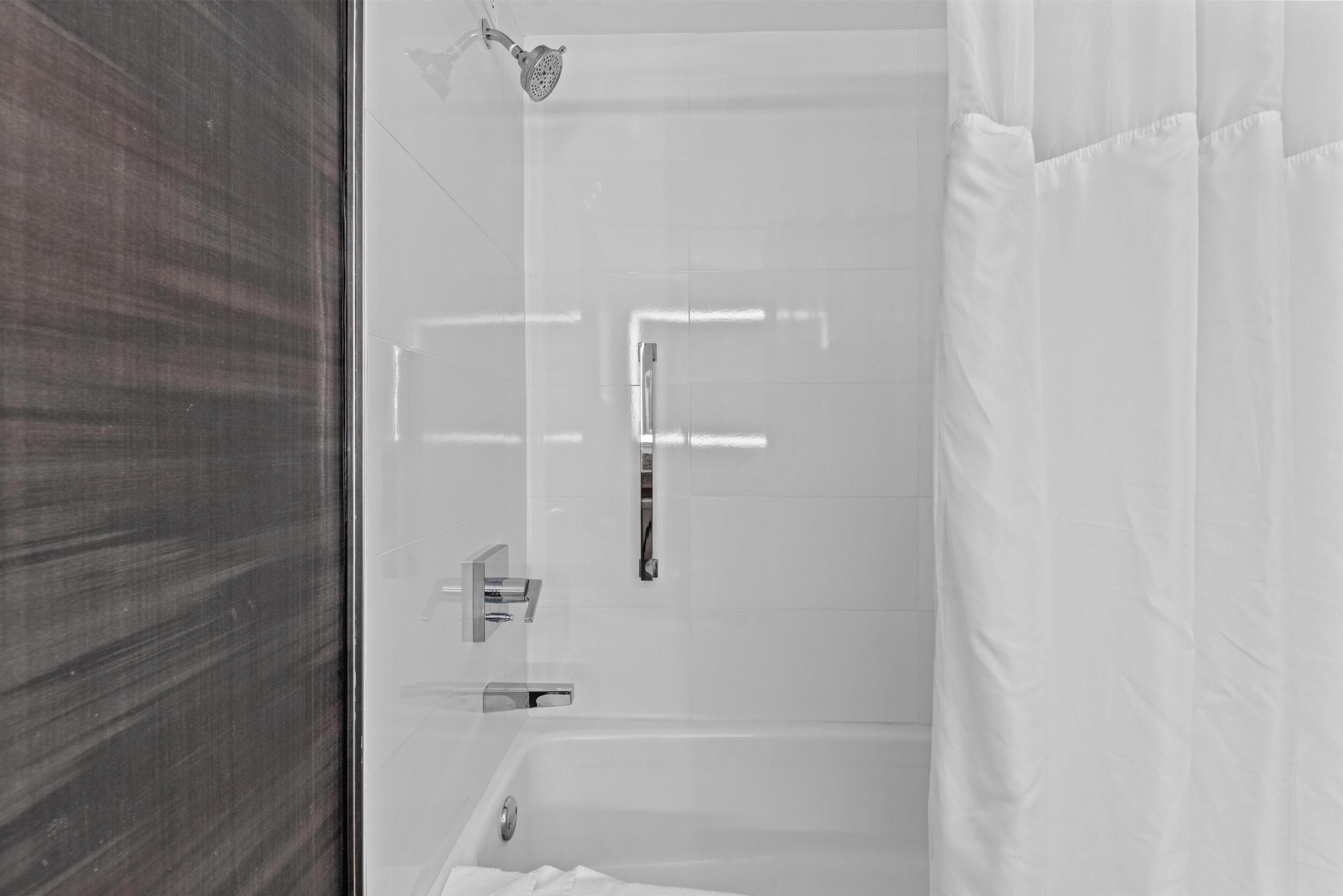 Een moderne badkamer met een glazen douchecabine, een bad en een toilet.