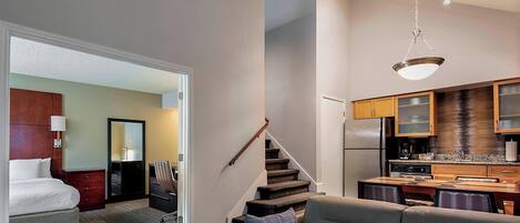 Una habitación de hotel moderna con sofá, comedor y cocina.