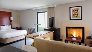 Habitació d'hotel amb llit, escriptori amb ordinador, televisió, llar de foc i sofà.