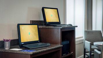 Two laptops on a desk with a keyboard and mouse, a notepad, and a pen holder.