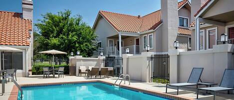 A swimming pool with lounge chairs and a covered patio area.