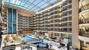 A multi-level hotel atrium with a central pool, outdoor seating areas, and multiple balconies. - Embassy Suites by Hilton Anaheim North (Anaheim)