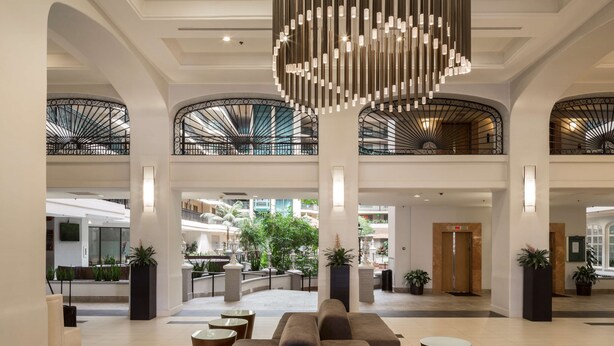 A spacious lobby with a high ceiling, large seating area, and a central chandelier. - Embassy Suites by Hilton Anaheim North (Anaheim)