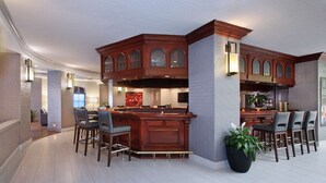 A modern kitchen with a bar area, featuring a large island with bar stools, a built-in oven, and a backsplash with a geometric pattern. - Embassy Suites by Hilton Anaheim North (Anaheim)